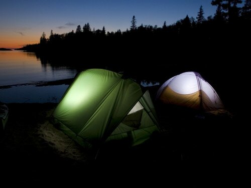 A pair of tents glow at dusk during a sea kayaking trip at Chalfant Cove in Lake Superior Provincial Park near Wawa Ontario Canada.